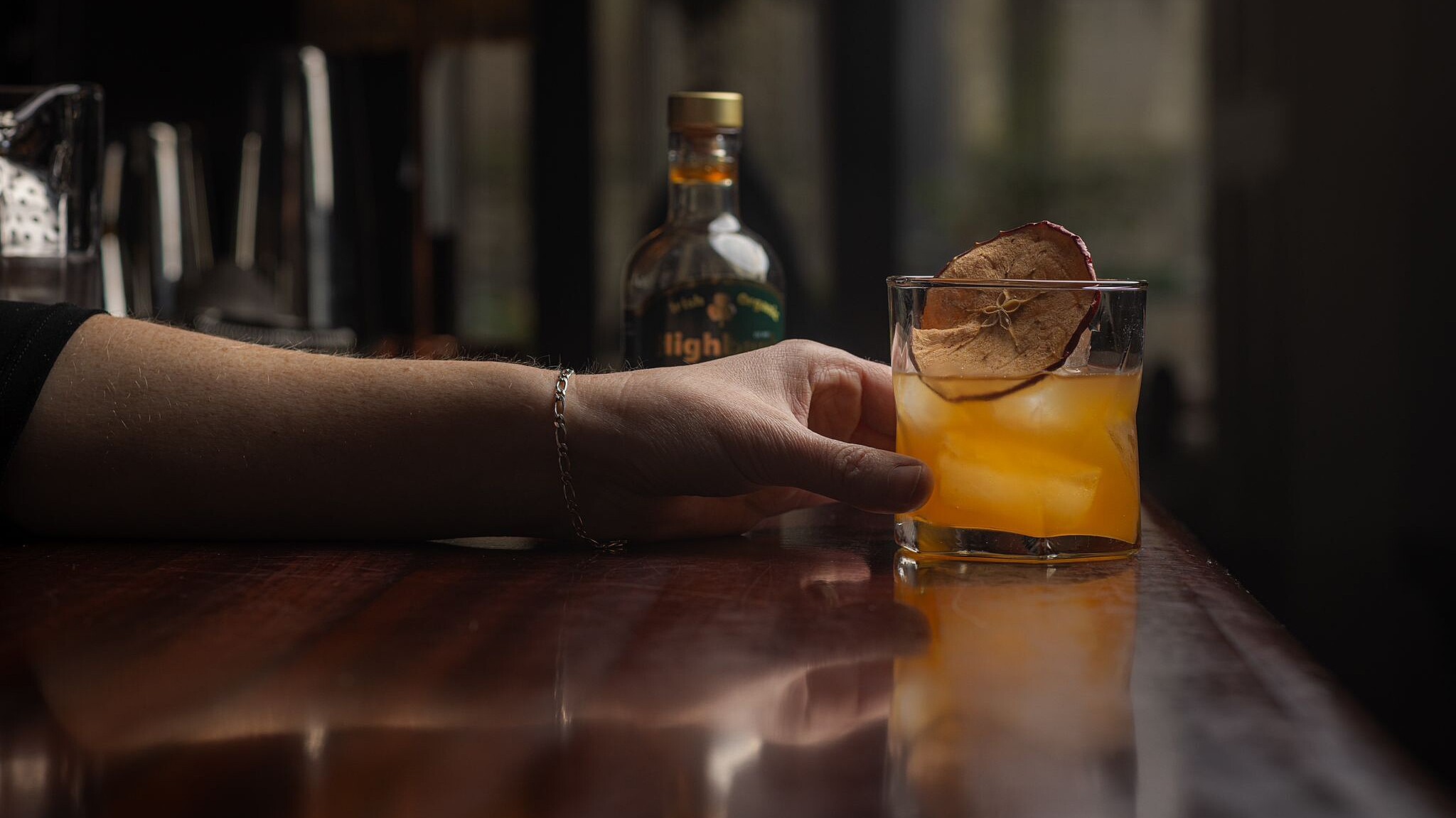 Cocktail being handed over counter with bottle of Highbank Orchards syrup in the background