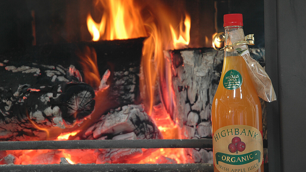 Bottle of Mulled Highbank Apple Juice in front of a log fire