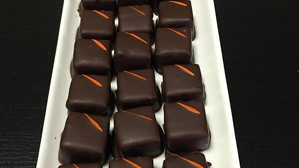 white tray of square dark chocolates with red stripe on top