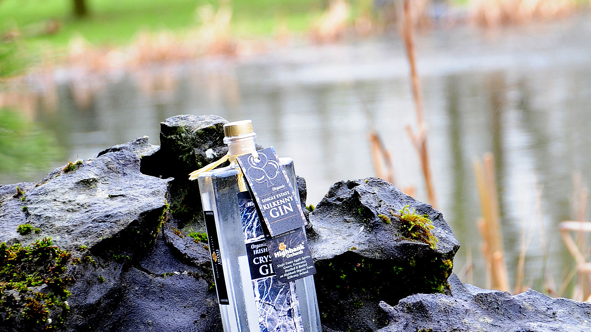 500ml square bottle of Kilkenny Crystal gin in a jagged rock beside a lake