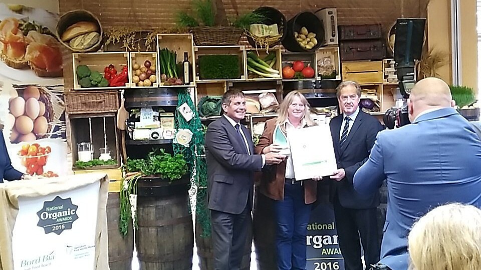 background of vegetables in boxes at presentation of National Organic Chef Award 2016 three people in picture with photograper