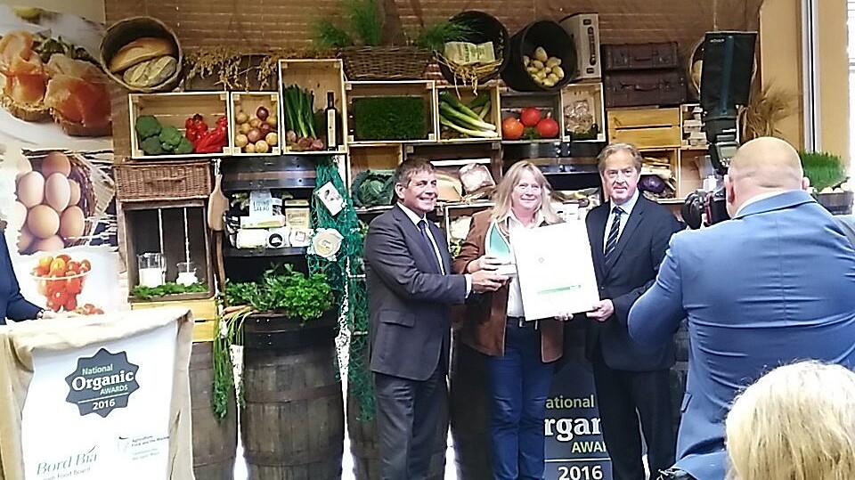 background of vegetables in boxes at presentation of National Organic Chef Award 2016 three people in picture with photograper