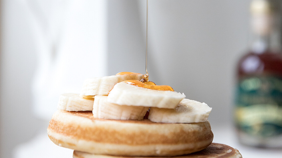 stack of pancakes with Highbank orchard syrup drizzling down on them. White jug in background