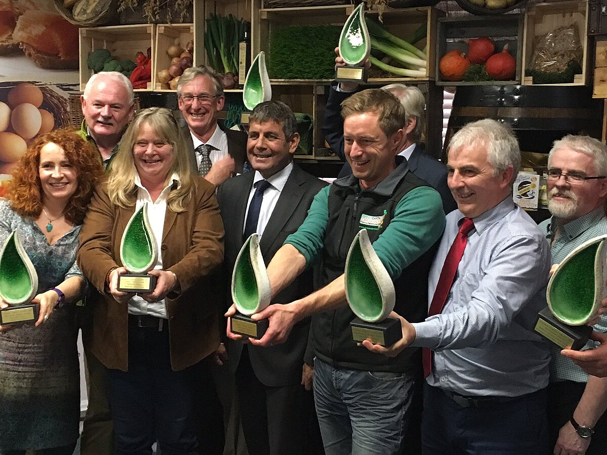 9 people all with green artwork awards in a line at the National Organic Awards