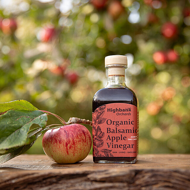 250ml Oak aged apple balsamic vinegar beside apple and leaves on wood. Red label.