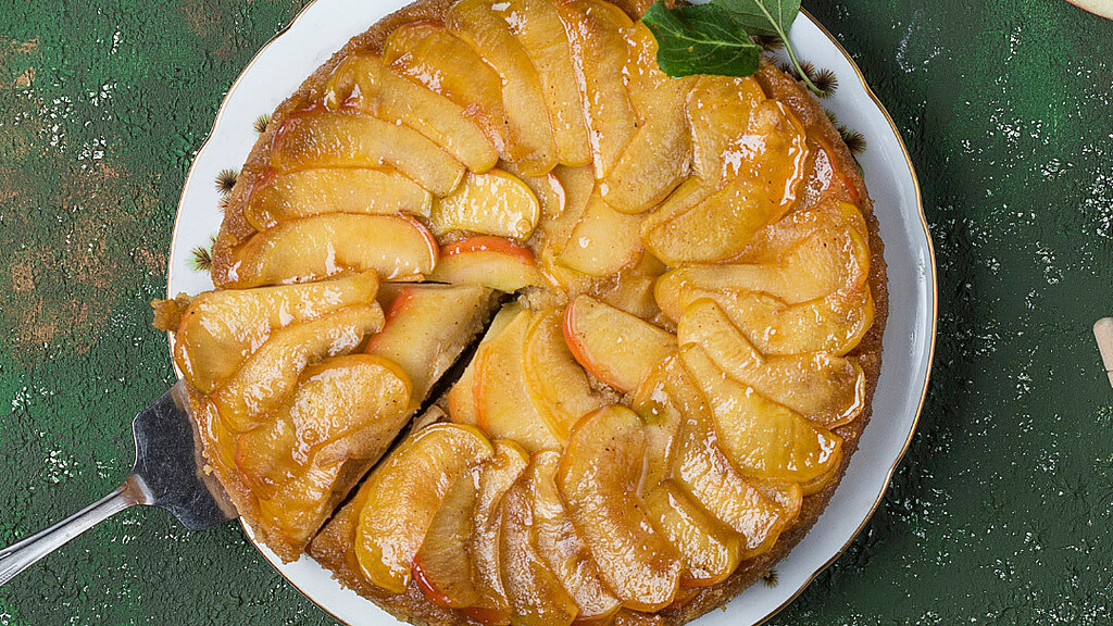 Birds eye view of Blusher apple tart on green table with apples and leaves