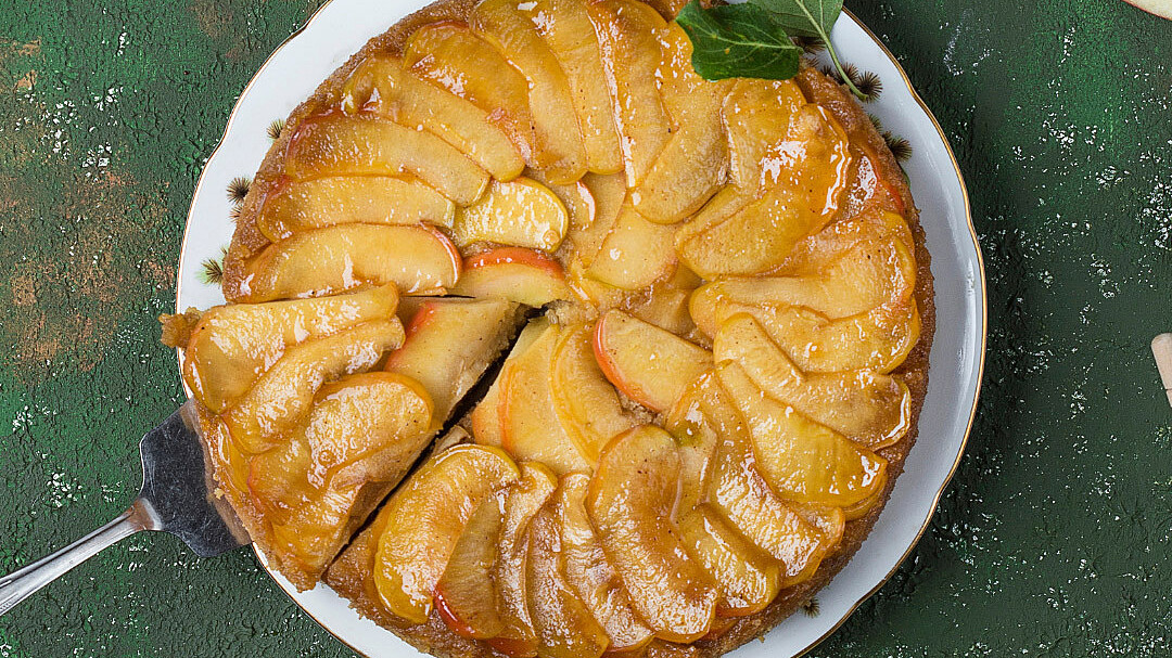 Birds eye view of Blusher apple tart on green table with apples and leaves