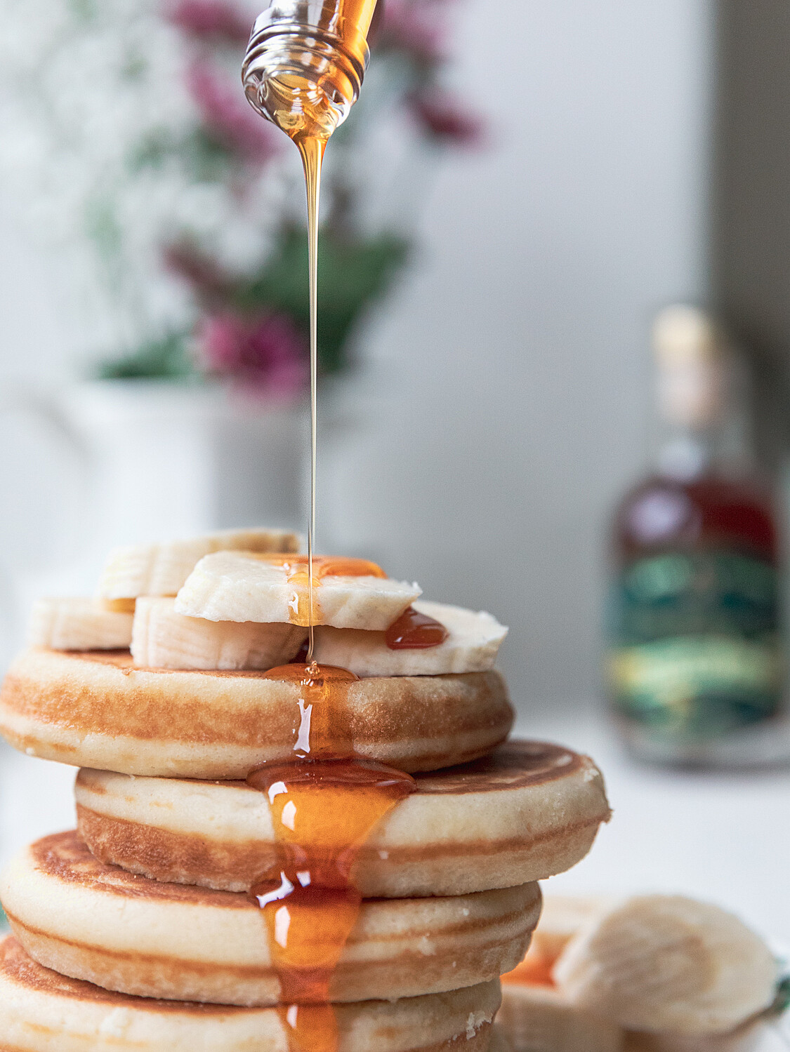 stack of pancakes with Highbank Orchard Syrup being drizzled down on them. Orchard syrup bottle in background