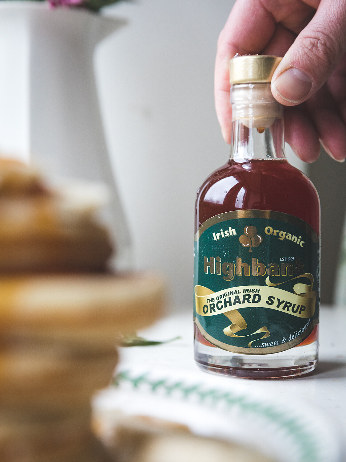 200ml bottle of Highbank Orchard Syrup being shown beside pancakes